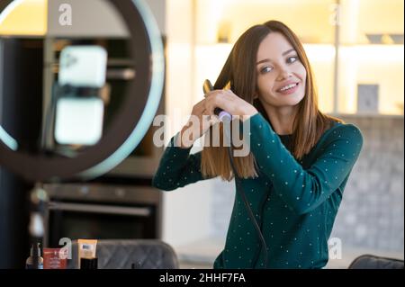 Lächelnde junge Frau zeigt Tipps zur Haarpflege Stockfoto