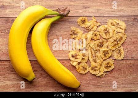 Gesunder Snack. Hausgemachte, dehydrierte Bananenchips und frische Äpfel auf einem rustikalen Holzhintergrund Stockfoto