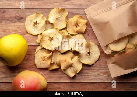 Gesunder Snack. Hausgemachte, dehydrierte Apfelchips und frische Äpfel auf einem rustikalen Holzhintergrund Stockfoto
