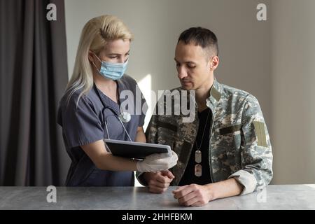 Arzt mit Militäroffizier Patient im Krankenhaus Stockfoto