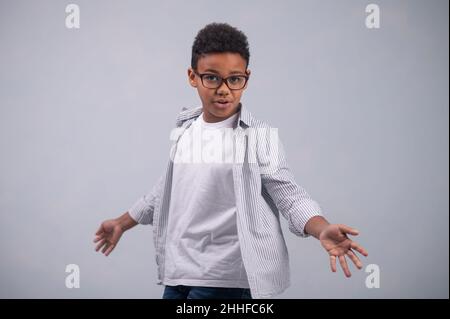 Afroamerikanisches Kind in einer Brille, die seine Offenheit demonstriert Stockfoto