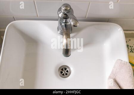 Weißes Waschbecken auf Holztheke mit einem Spiegel darüber. Innenausstattung des Badezimmers. Stockfoto