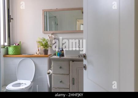 Weißes Waschbecken auf Holztheke mit einem Spiegel darüber. Innenausstattung des Badezimmers. Stockfoto