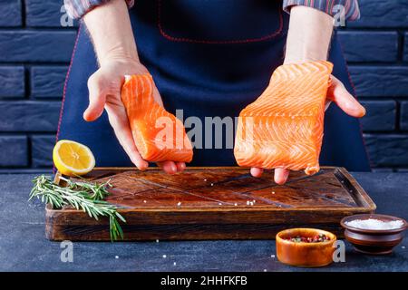 Der Mann zeigt Lachsfilet. Der Küchenchef zeigt ein Fischfilet in einer Restaurantküche Stockfoto