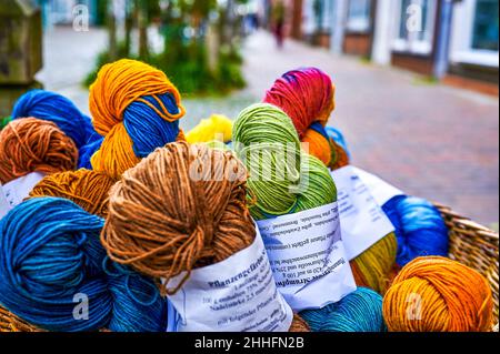 Verschiedene Skeins aus bunt gefärbter Wolle in einem Korb vor einem Laden. Stockfoto