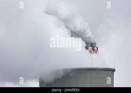 Aus dem Kamin eines Kohlekraftwerks kommen dichte Rauchwolken. Aufnahme an einem bewölkten Tag, gleichmäßiges und weiches Licht. Stockfoto