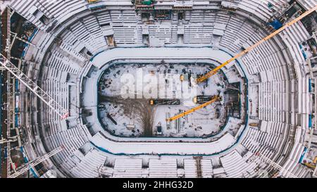 Luftaufnahme der Baustelle eines großen Sportstadions. Baukräne heben Lasten. Stockfoto