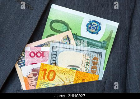 Banknoten verschiedener Währungen in Businessman-Tasche. Geld in der Tasche des Business-Anzugs. Weltweite Währung Stockfoto