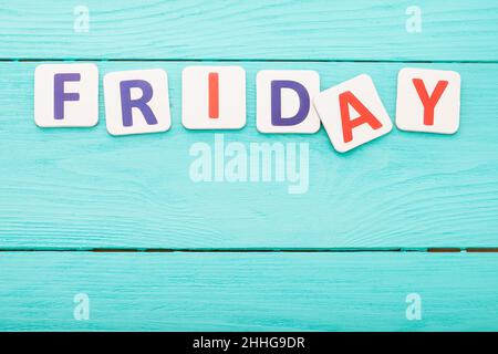 Wort freitag Buchstaben auf blauem Holzhintergrund. Verkäufe am Black friday. Draufsicht. Speicherplatz kopieren. Modell Stockfoto
