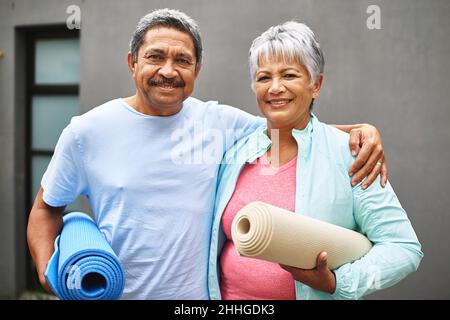 Mach dich fit, bleibe fit. Porträt eines glücklichen älteren Paares, das seine Übungsmatten im Freien trägt. Stockfoto