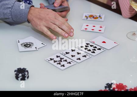 Die Hände des Mannes mischen Karten. 2 Asse auf dem Tisch in einem Pokerspiel mit Chips, Karten auf dem Tisch. Genießen Sie den Moment, digitale Entgiftung mit Freunden. Lifestyle-Fotografie. Ehrliche Momente. Selektiver Fokus Stockfoto