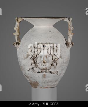 Terrakotta-Vase mit zwei Henkelbeinen Ende 4th–Anfang 3rd Jh. v. Chr. Griechisch, Süditalien, Apulien, Canosan Diese Vase ist eine Variante des Trichtergefäßes mit Relieftafeln 06.1021.248. Die zugrunde liegende Form ist vergleichbar. Die Dekoration hier ist noch skulpturaler, mit den beiden Griffen in Form von Erotes; Gipskopien ersetzen die Originale, die verloren gehen. Die prächtig taktile Medusa auf der Vorderseite des Körpers kann ihre altehrwürdige Funktion als Hüterin und Abwehr des Bösen erfüllen. Auf der Kante zwischen ihren Flügeln stand einst eine Statuette, vier solche Vasen waren in der Beerdigung. Diese gehört zu Th Stockfoto