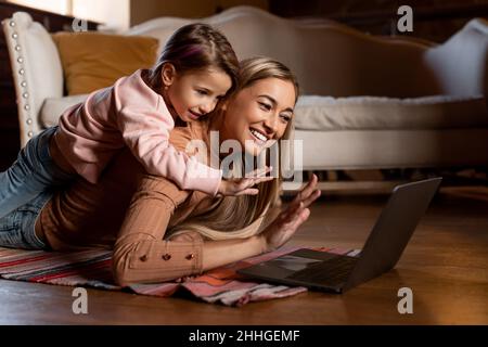 Lächelnde Mutter und Mädchen mit Laptop winkende Hand Stockfoto