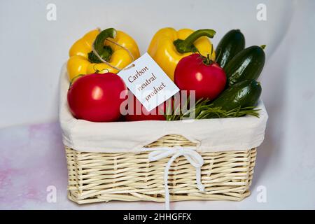 Korbkorb mit klimaneutralem Produktlabel auf frischem Gemüse. CO2-Kennzeichnung. Netto kohlenstofffrei, emissionsfrei. Bio-Landwirtschaftsprodukte vom lokalen Markt. Frische Tomaten, Gurken, Paprika Stockfoto