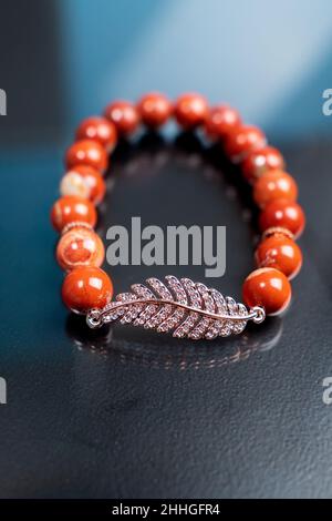 Armband aus Natursteinen auf der Hand aus Naturstein Jaspis. Handgefertigter Schmuck. Selektiver Fokus. Vertikales Foto Stockfoto