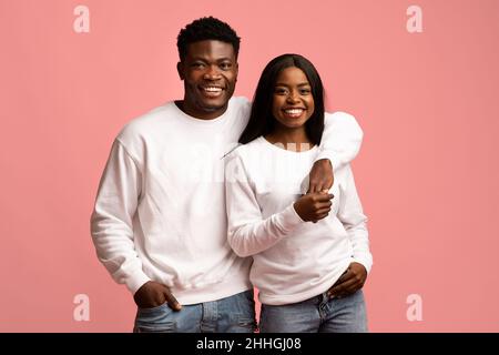 Schöne afroamerikanische Liebhaber in ähnlichen Outfits auf rosa Stockfoto