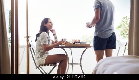 Sonntagsbrunch ist Bindungszeit. Aufnahme eines glücklichen jungen Paares, das zu Hause ein gemütliches Frühstück auf dem Balkon hat. Stockfoto