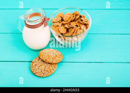 Haferflocken und Kekse mit Milchkännchen auf blauem Holzhintergrund. Draufsicht Stockfoto