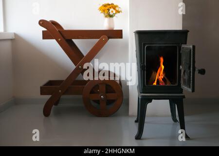 Helles Wohnzimmer mit Kamin. Kamin aus Metall. Entspannendes Ambiente und Heizung. Stockfoto