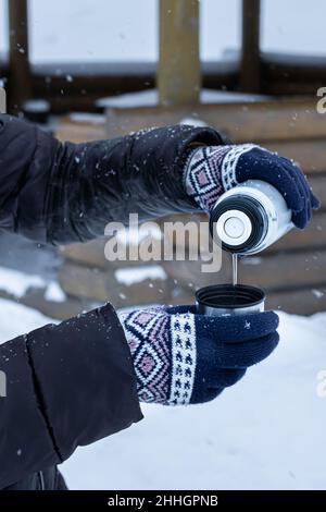 Eine Frau mit Gewicht gießt Tee aus einer Thermoskanne in einen Becher. Hochwertige Fotos Stockfoto