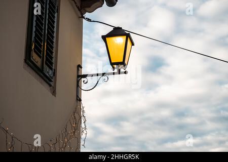 Straßenlaterne, die während des Abenduntergangs in der Straße von Rovinj, Kroatien, leuchtet Stockfoto