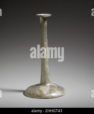Parfümflasche aus Glas 2nd–3rd Jahrhundert n. Chr. Römischer Kerzenständer unguentarium.farblos mit bläulichem Farbton.Röhrenrand ausgeklappt, über und in; zylindrischer Hals nach unten aufflackend; konvexer Körper, ausgebogen und scharf nach unten; eingedrungener Boden mit zentralem tritt.gebrochener und reparierter Körper mit kleinem Loch in der Kante an der Basis; viele Blasen und Blasen; Lochfraß, Irideszenz und Flecken von cremig-brauner Verwitterung. Farblose geblasenes Glas 'Candle-Stick' Vase mit sehr langem Hals und breiter Basis. Parfümflasche aus Glas. Roman. 2nd–3rd Jahrhundert n. Chr. Glas; geblasen. Mittelbritisch. Glas Stockfoto