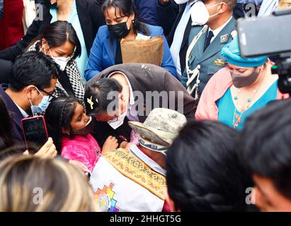 24th. Januar 2022, La Paz, Bolivien: Ein junges Mädchen in Rosa spricht beim heute gestarteten Alasitas-Festival mit dem bolivianischen Präsidenten Luis Arce Catacora (links von der Mitte). Rechts trägt die Ministerin der Präsidentschaft María Nela Prada Tejada einen türkisfarbenen Kopfschmuck. Alasitas ist ein beliebtes Fest, das im gesamten bolivianischen altiplano, insbesondere in La Paz, gefeiert wird. Es hat sehr alte Ursprünge - traditionell würden die Aymara-Leute Rituale durchführen und ihren Göttern Miniaturen anbieten, wobei die Idee war, dass diese dann im kommenden Jahr empfangen würden. Stockfoto