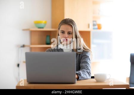 Junge Frau mit Laptop zu Hause Stockfoto