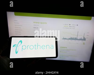 Person mit Mobiltelefon und Logo des irischen Biotechnologie-Unternehmens Prothena Corporation plc auf dem Bildschirm vor der Webseite. Konzentrieren Sie sich auf die Telefonanzeige. Stockfoto