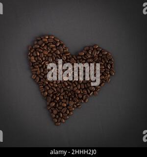 Aromatische Herzform aus Hunderten von köstlichen, knusprigen und speziellen Kaffeebohnen-Sorten. Grauer Hintergrund. Foto von Kaffeeliebhabern. Verlockend Stockfoto
