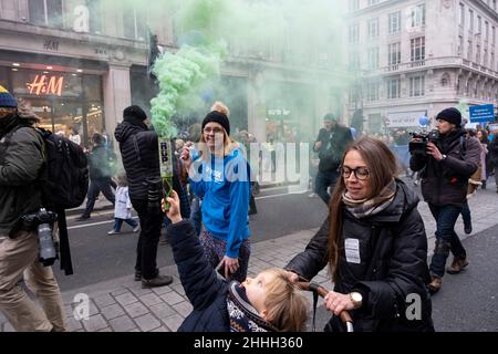 Der junge Protestler lässt bei der World Wide Rally for Freedom Protest im Zentrum von London einen grünen Rauchflackern aufflackern gegen die Pläne der Regierungen für verpflichtende Covid-Impfungen für alle NHS-Arbeiter an vorderster Front, die am 22nd. Januar 2022 in London, Großbritannien, in Kraft treten sollen. NHS-Mitarbeiter, die gegen das Mandat vorgehen und Impfjabs ablehnen, könnten sich dem Sack stellen. Die World Wide Demonstration oder World Wide Rally for Freedom ist eine internationale Protestveranstaltung der Gemeinschaft, bei der die Bürger gegen Einschränkungen im Zusammenhang mit dem Coronavirus in ihren Ländern vorgehen. Stockfoto