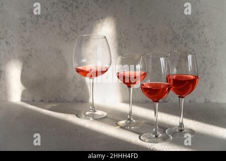 Rotwein in Gläsern auf weißem Steingrund. Konzept der Weinprobe. Viele Gläser Rotwein bei einer Weinprobe. Das Konzept von Rotwein und Vielfalt Stockfoto