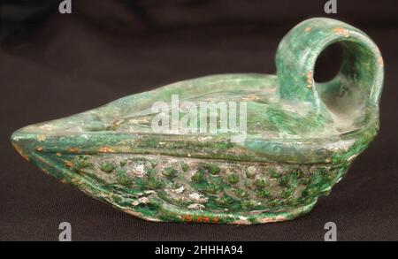Lampe 9th Jahrhundert die flachen, offenen Lampen, die früher im Nahen Osten verwendet wurden, wurden durch tiefere gequetschte Schalen ersetzt, die in hellenistischer Zeit aus Griechenland importiert wurden. Charakteristisch für die römische Töpfertradition sind jedoch die Reliefverzierung und die grünen oder honigfarbenen Glasuren. Diese Lampen verbrannten Olivenöl durch einen Faserdocht. Lampe. 9th Jahrhundert. Steingut; geformt, gerutscht und glasiert. Wird Syrien zugeschrieben, wahrscheinlich Aleppo. Keramik Stockfoto