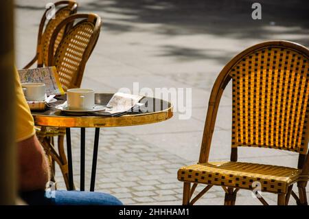 PARIS, FRANKREICH - 14. AUGUST 2014: Tourist sitzt auf der Terrasse des Le Nemours Café mit einer Tasse Kaffee, Stadtführer und Karte. Dieses beliebte Café i Stockfoto