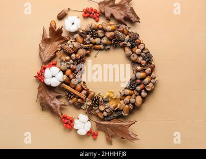 Kranz aus schönem Herbstdekor und Baumwollblumen auf farbigem Holzhintergrund Stockfoto