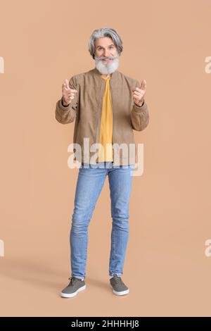 Senior-Mann in stilvoller Jacke auf beigem Hintergrund Stockfoto