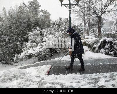 Istanbul, Türkei. 24th Januar 2022. Am 24. Januar 2022 räumt ein Mann in einem Park in Istanbul, Türkei, Schnee. Der Flughafen Istanbul sagte am Montag aus Sicherheitsgründen alle Flüge aus, nachdem die türkische Metropole und das Finanzzentrum von einem starken Schneesturm durchgefegt worden waren, so das Flughafenmanagement. Quelle: Shadati/Xinhua/Alamy Live News Stockfoto