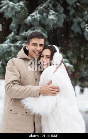 Liebevolles Paar umarmt sich im Park am verschneiten Wintertag Stockfoto