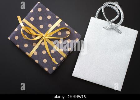 Geschenkbox in Tupfen und Papiertasche auf schwarzem Hintergrund. Draufsicht und Kopierbereich. Modell Stockfoto