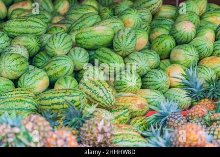 Viele Ananas und Wassermelonen am Boden auf dem Lebensmittelmarkt in Sansibar, Tansania Stockfoto