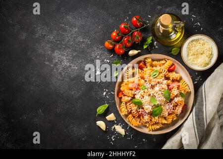 Italienische Pasta alla arrabiata mit Basilikum und Parmesan auf dunklem Tisch. Stockfoto