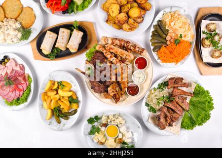 Ein gedeckter Tisch mit vielen verschiedenen Gerichten zum Abendessen. Viel Essen auf einem weißen, isolierten Hintergrund. Stockfoto