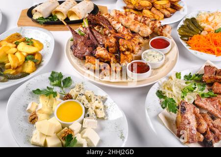 Ein gedeckter Tisch mit vielen verschiedenen Gerichten zum Abendessen. Viel Essen auf einem weißen, isolierten Hintergrund. Stockfoto
