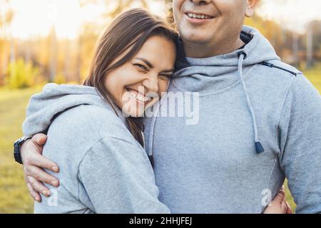 Porträt einer lächelnden Frau, die ihren Mann umarmt und lächelt. Paar mittleren Alters umarmt im Park, tolles Design für jeden Zweck. Stockfoto