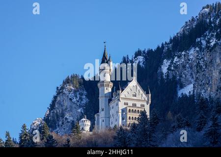 Blick im Winter vom Dorf Schwangau auf das königliche Schloss Neuschwanstein, umgeben von Wald in den Bergen, von König Ludwig II. Stockfoto