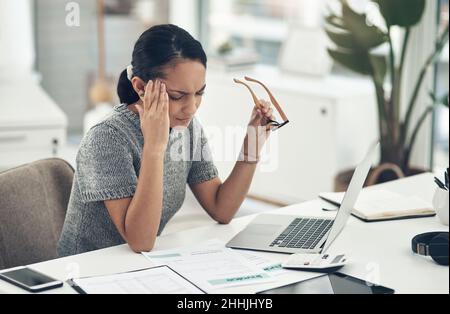 Überarbeitet und fühlt es. Aufnahme einer jungen Geschäftsfrau, die gestresst in einem Büro arbeitet. Stockfoto