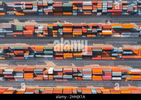 Vollständige Dronen-Ansicht von mehrfarbigen Frachtcontainern, die in parallelen Linien auf dem Schiffsdock angeordnet sind Stockfoto