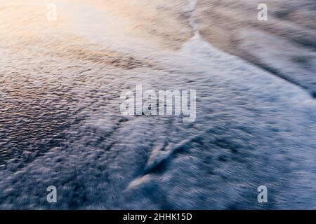 Von oben schaumig Wellen des Ozeans Rollen auf Sandstrand Stockfoto
