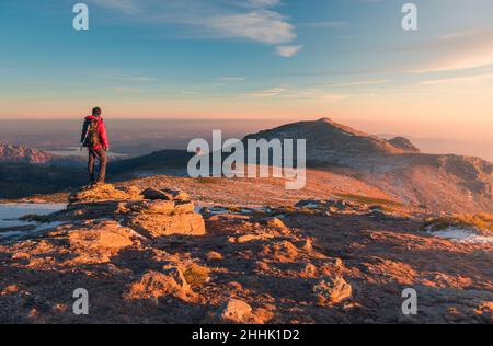 Rückansicht eines entfernten anonymen Wanderers, der am Wintertag auf der Sierra de Guadarrama-Bergkette während des Trekkings in Spanien steht Stockfoto