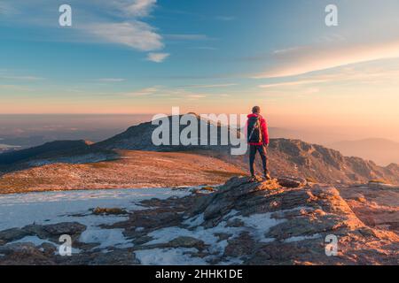 Rückansicht eines entfernten anonymen Wanderers, der am Wintertag auf der Sierra de Guadarrama-Bergkette während des Trekkings in Spanien steht Stockfoto